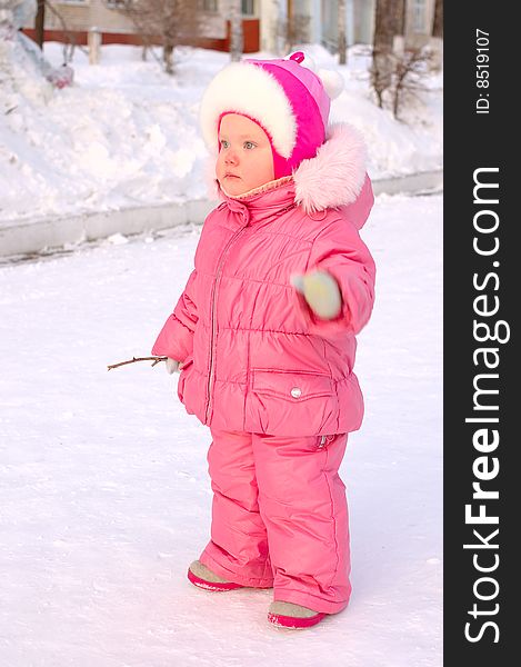 Pretty little girl in winter outerwear with branch on the snow. Pretty little girl in winter outerwear with branch on the snow.