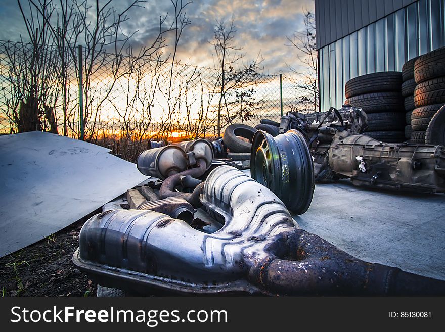 A junk yard with old car parts in the sunset.