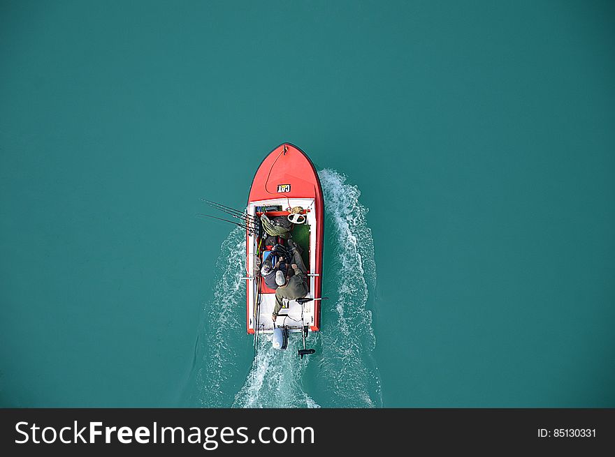 An aerial view of fishermen on a motor boat on a turquoise water surface. An aerial view of fishermen on a motor boat on a turquoise water surface.