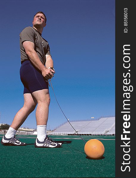 Man Wearing Grey Shirt Swinging Orange Ball