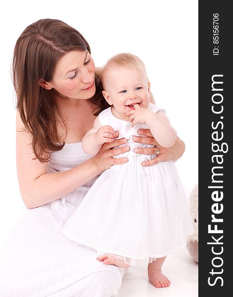 Brown Haired Woman Wearing White Strapless Dress Holding Bay Wearing White Sleeveless Dress