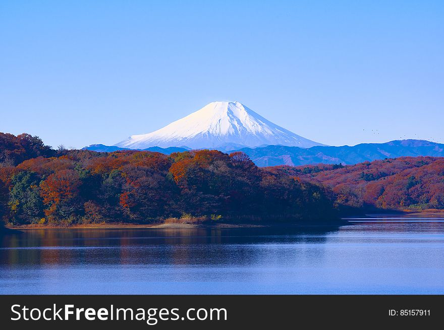 Landscape of fall foliage around alpine lake with snow capped mountains in Japan on sunny day. Landscape of fall foliage around alpine lake with snow capped mountains in Japan on sunny day.