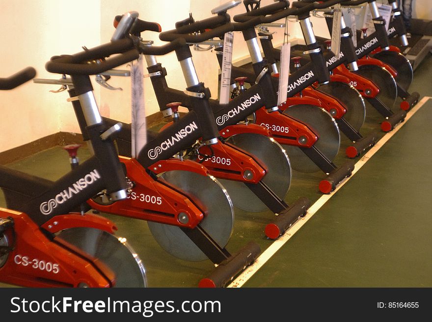 Row of empty exercise bikes inside fitness center.