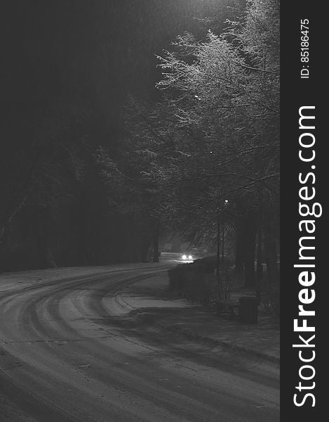 Car driving on curvy snow covered road at night in black and white. Car driving on curvy snow covered road at night in black and white.