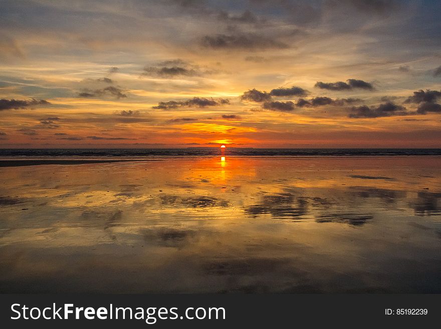 Sunset and clouds reflecting in still waters on horizon. Sunset and clouds reflecting in still waters on horizon.
