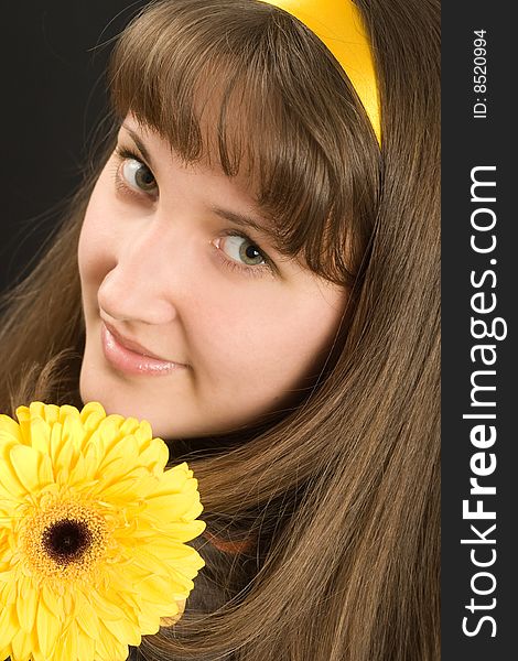 Portrait of beautiful girl with yellow flower on black