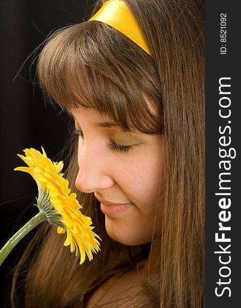 Portrait of beautiful girl with yellow flower on black