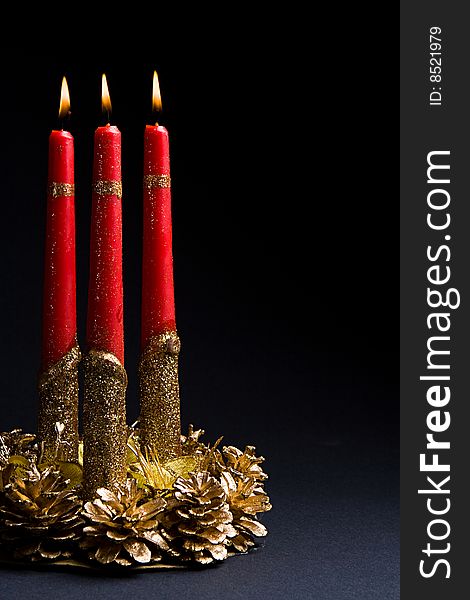 Beautiful red candles in a candlestick from gold cones against a dark background. Beautiful red candles in a candlestick from gold cones against a dark background