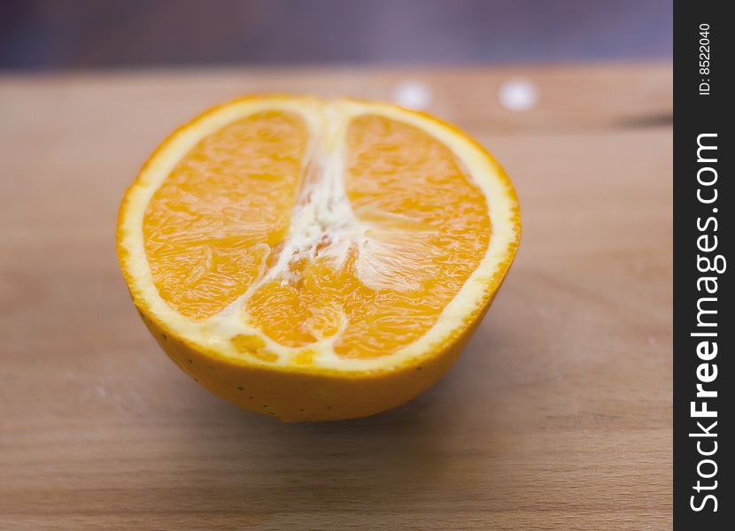 Half-orange lies on a wooden board, small depth of sharpness