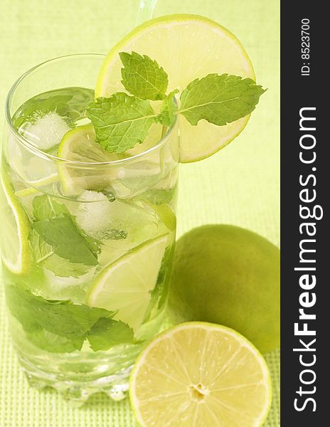 Mojito cocktail with lime, mint leaves and ice on green background. Mojito cocktail with lime, mint leaves and ice on green background