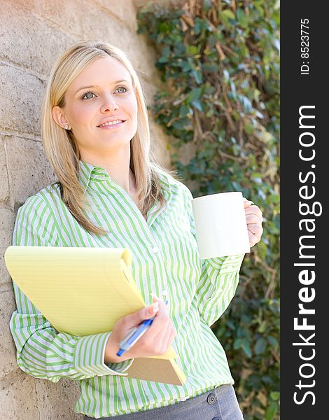 Business woman standing outside with a coffee and a notebook