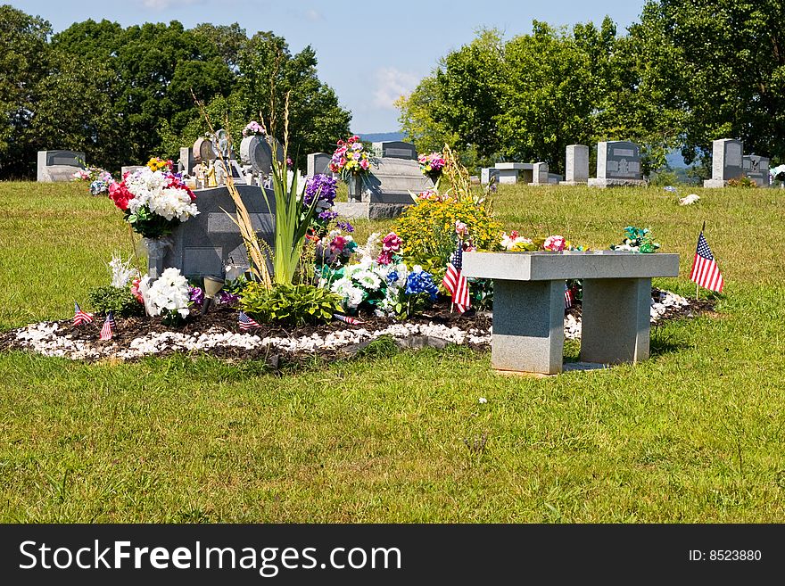 Cemetery with focus on a dual grave plot with a lot of flowers and ornaments. Cemetery with focus on a dual grave plot with a lot of flowers and ornaments.