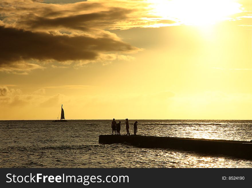 Sunset on pier, silhouette of family and sail boat