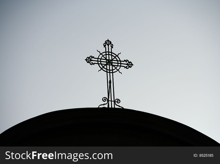 A shilouette of a cast iron cross on a church dome against a dull sky. A shilouette of a cast iron cross on a church dome against a dull sky