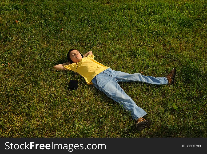 The young boy lying on the grass and listening to music. The young boy lying on the grass and listening to music