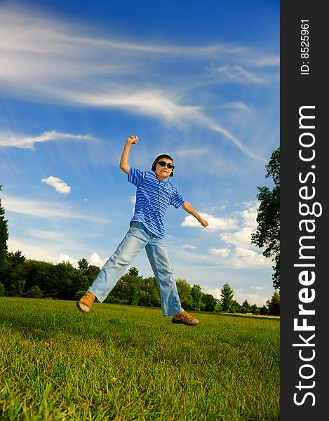 The happy boy in headphones jumps outdoors