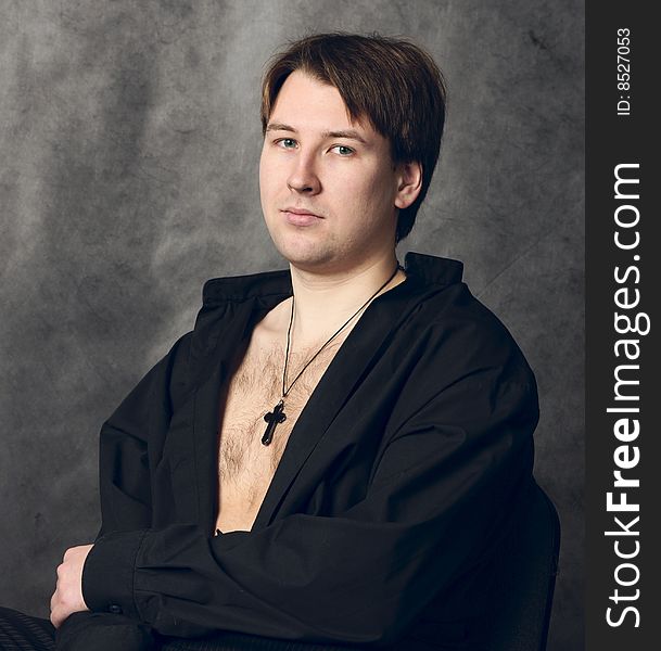 Studio portrait of a young man with naked torso and black cross