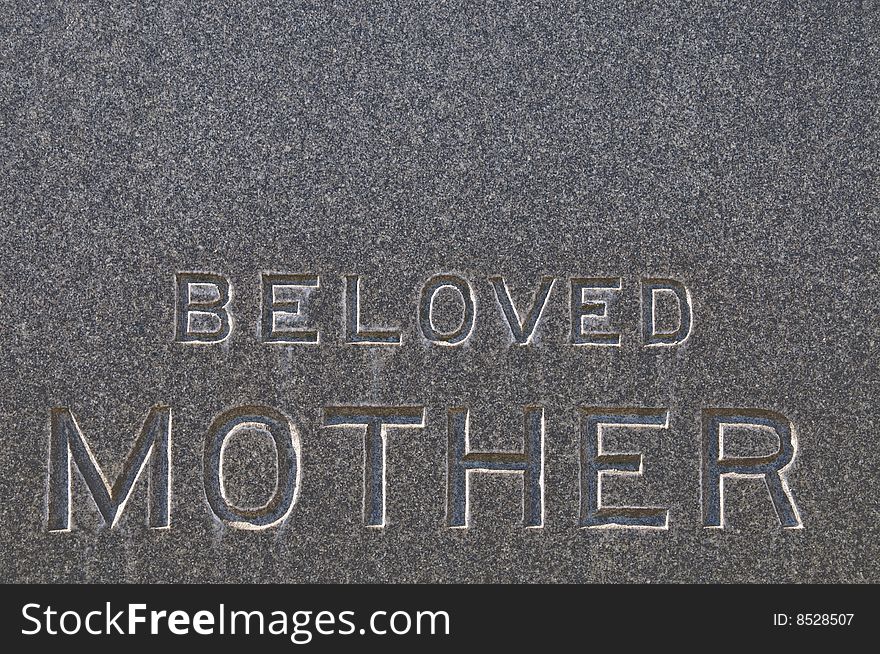 Beloved Mother inscription on old grunge granite tombstone.