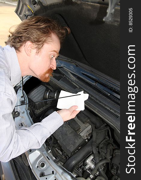 Funny man checking engine oil dipstick in car