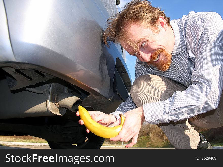 Man putting banana into car exhaust pipe