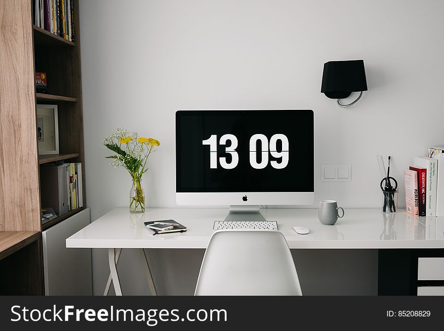 Apple computer screen with clock screen saver on white home office desk. Apple computer screen with clock screen saver on white home office desk.
