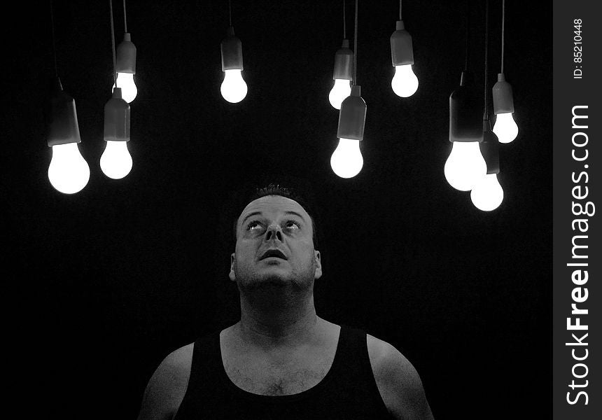 A black and white photo of a man looking at light bulbs. A black and white photo of a man looking at light bulbs.