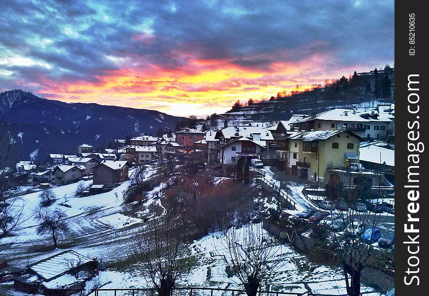 A snowy village with the sun setting in the distance. A snowy village with the sun setting in the distance.