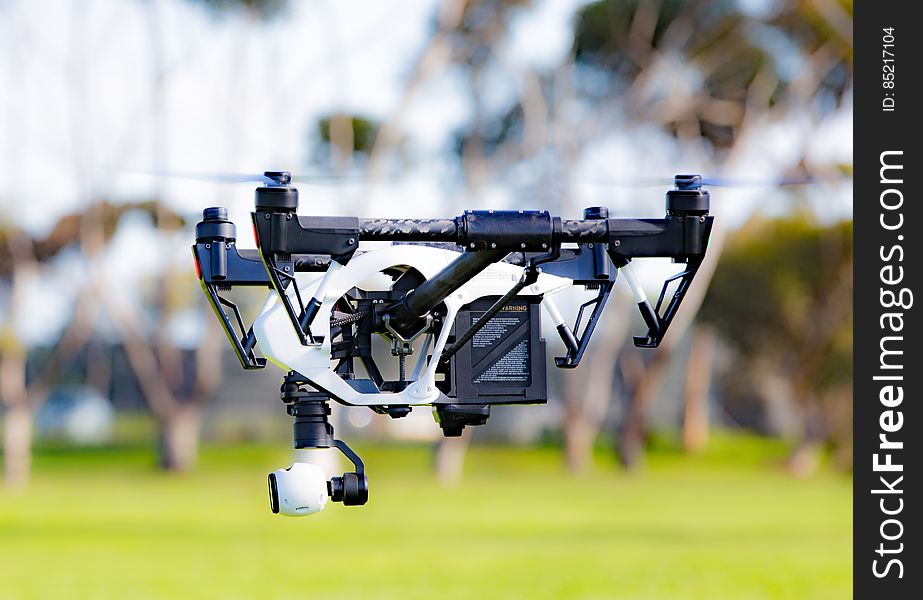 A quadcopter with a camera hovering over green field. A quadcopter with a camera hovering over green field.