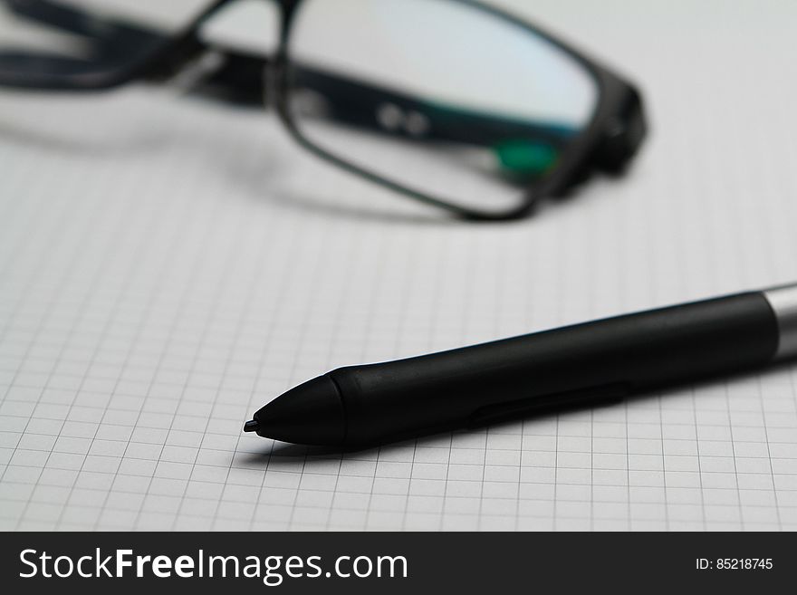 A close up of pencil and eyeglasses on graph paper.