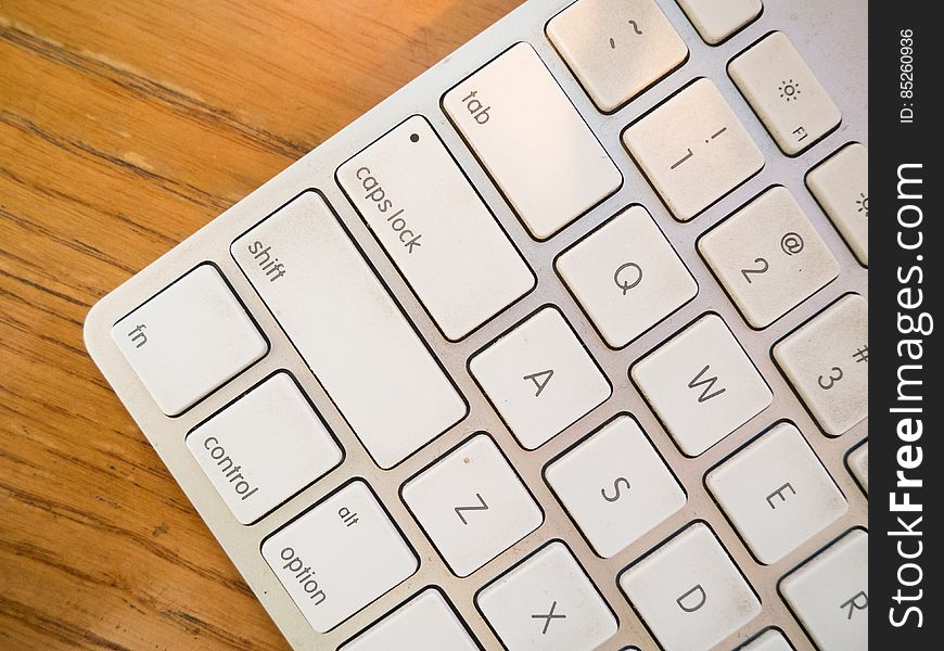 A close up of a white computer keyboard on a wooden background.