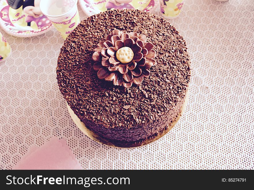 Overhead view of frosted and decorated chocolate cake on party table with paper plates and cups. Overhead view of frosted and decorated chocolate cake on party table with paper plates and cups.