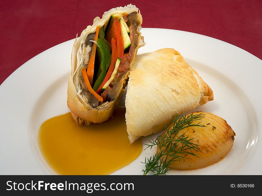 Fresh vegetables wrapped in filo pastry and presented on a white plate with mango sauce and crispy potato. Fresh vegetables wrapped in filo pastry and presented on a white plate with mango sauce and crispy potato