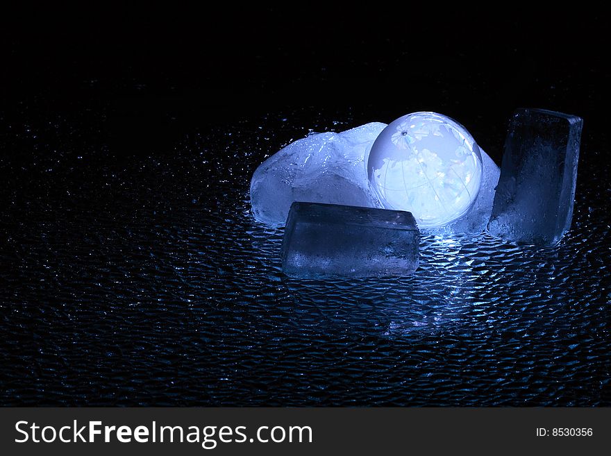 Dark background with glassy globe inside block of ice. Dark background with glassy globe inside block of ice