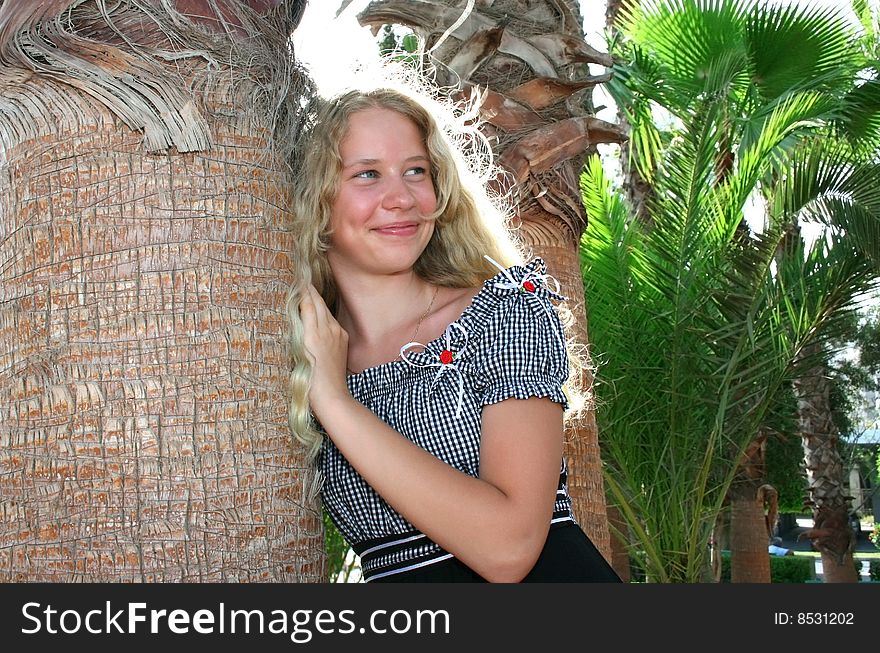 Pretty blond girl at the palm tree.