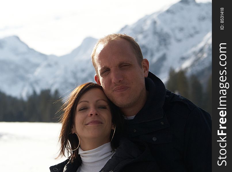 A young couple outdoor in a winter setting. The couple is hugging each other. A young couple outdoor in a winter setting. The couple is hugging each other.