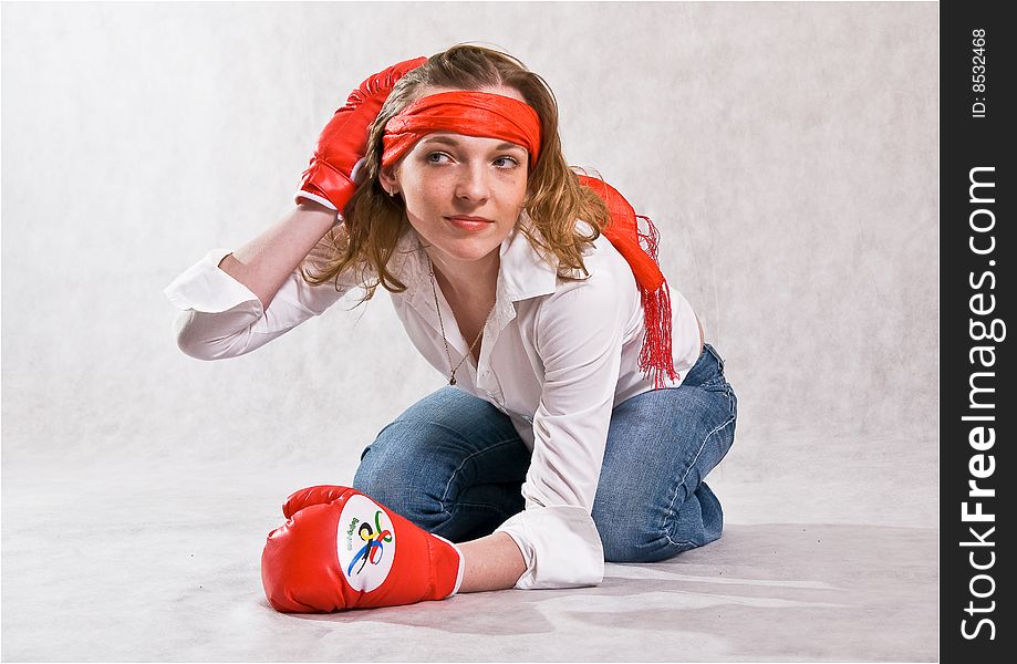 Girl is sitting with red boxing gloves, bending forward,  isolated on a white background. Girl is sitting with red boxing gloves, bending forward,  isolated on a white background