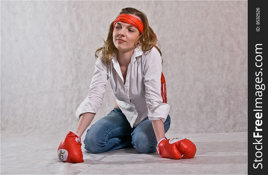 Girl is sitting with red boxing gloves on a white background. Girl is sitting with red boxing gloves on a white background