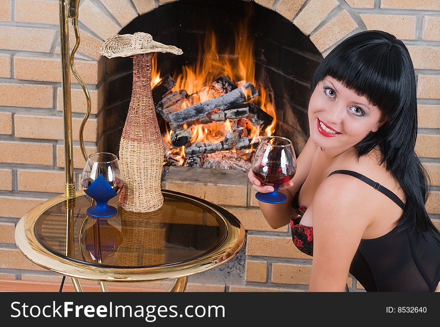 The woman the brunette drinks red wine at a fireplace. The woman the brunette drinks red wine at a fireplace.