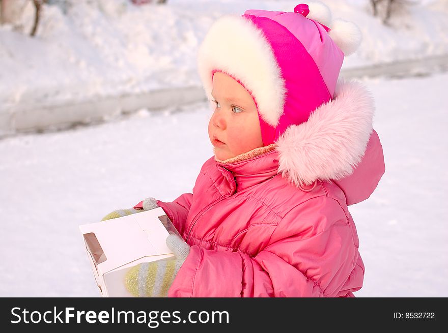 Pretty little girl in winter outerwear with and candy box on winter playground. Pretty little girl in winter outerwear with and candy box on winter playground.