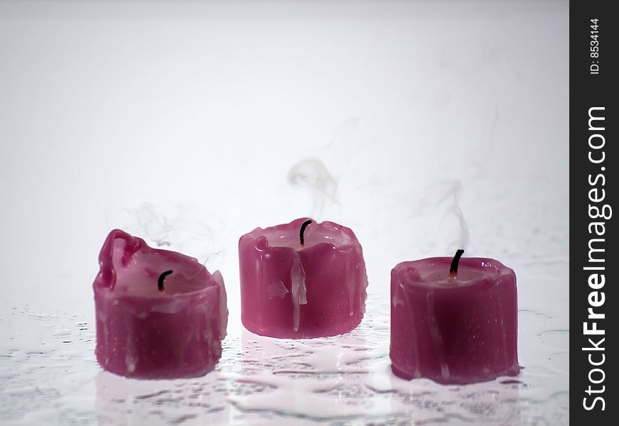 Candles, extinct standing on a wet surface that reflects light