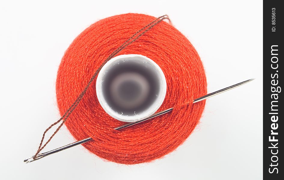 Close up of a red sewing spool with a needle