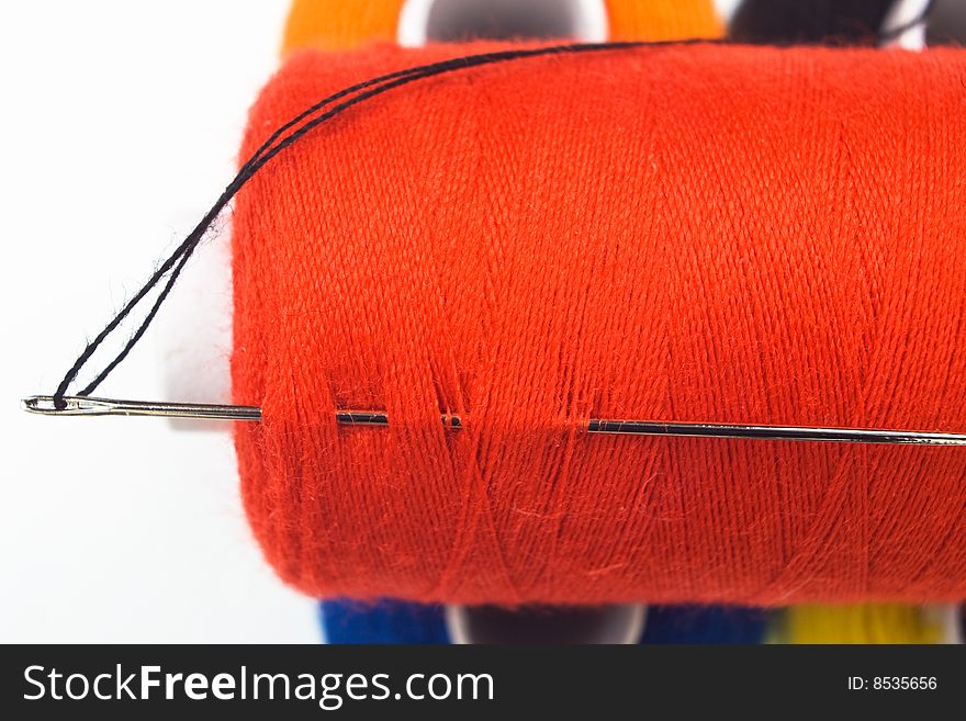 Close up of a red sewing spool with a needle