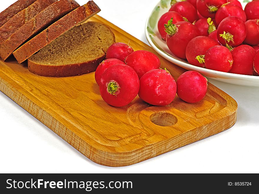 Garden radish and brown bread on wooden plate