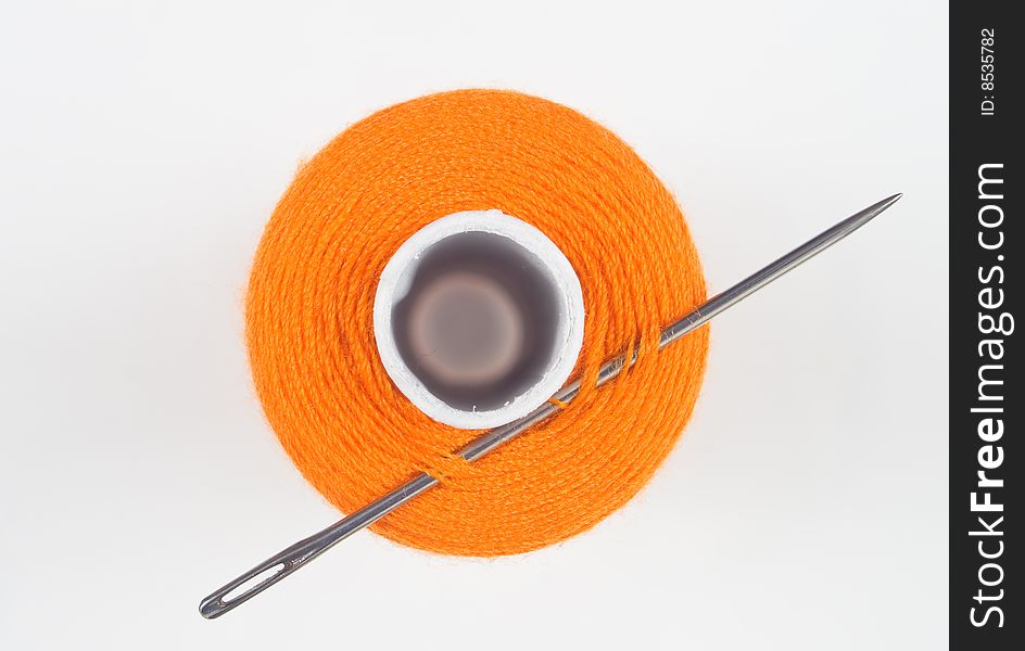 Close up of a orange sewing spool with needle
