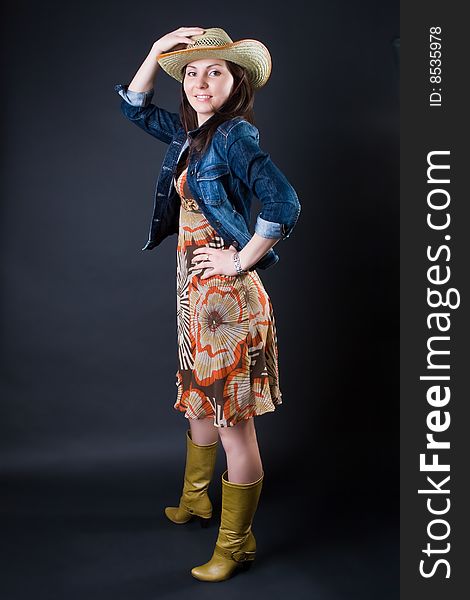 Girl in a cowboy's hat and a jeans jacket against a dark background. Girl in a cowboy's hat and a jeans jacket against a dark background