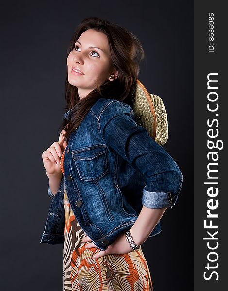 Girl in a cowboy's hat and a jeans jacket against a dark background. Girl in a cowboy's hat and a jeans jacket against a dark background