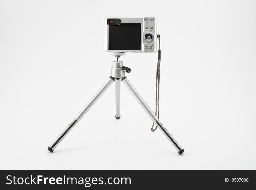 Small digital camera on small tripod against white background. Small digital camera on small tripod against white background