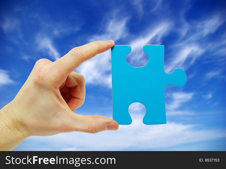 Puzzle in hand isolated on sky background