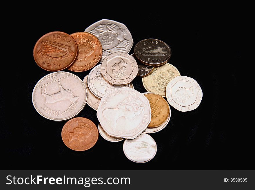 Assorted coins scattered on a black backround