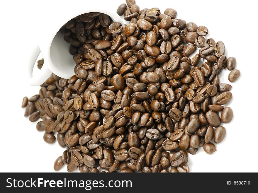 Photo of coffee beans spilling out of a white cup. Photo of coffee beans spilling out of a white cup.